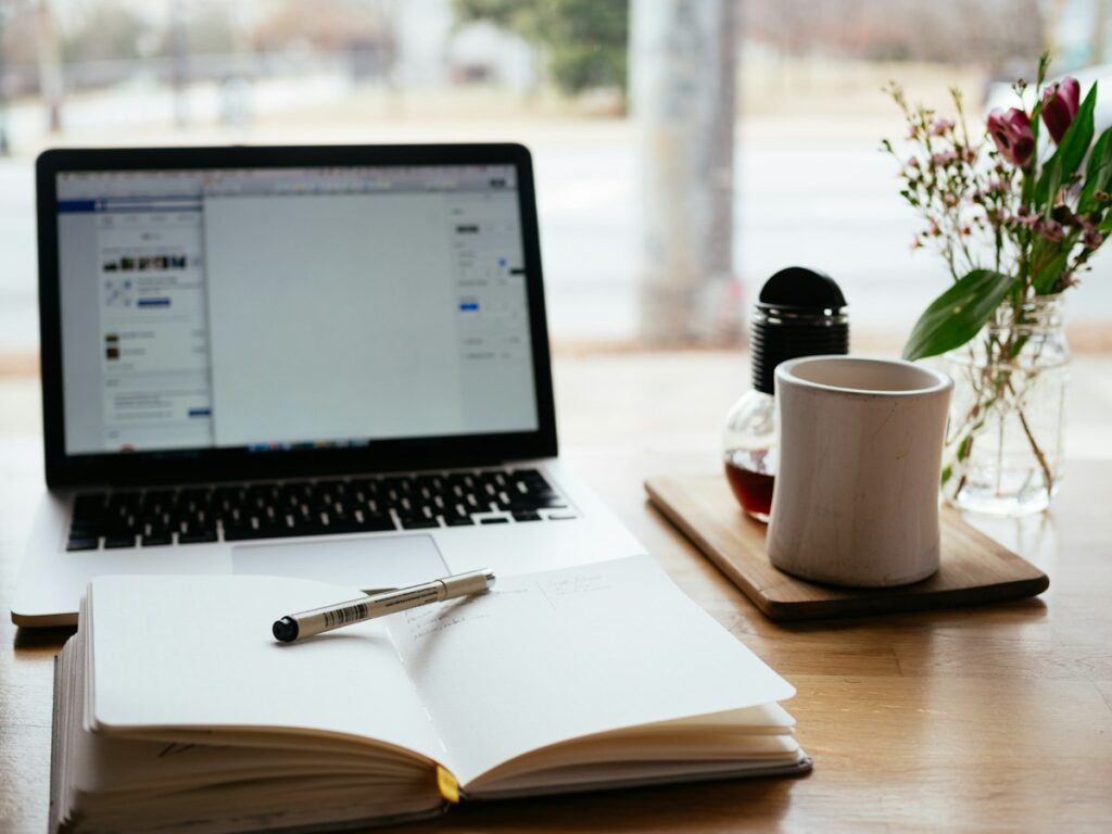 Laptop beside an open notebook on a desk